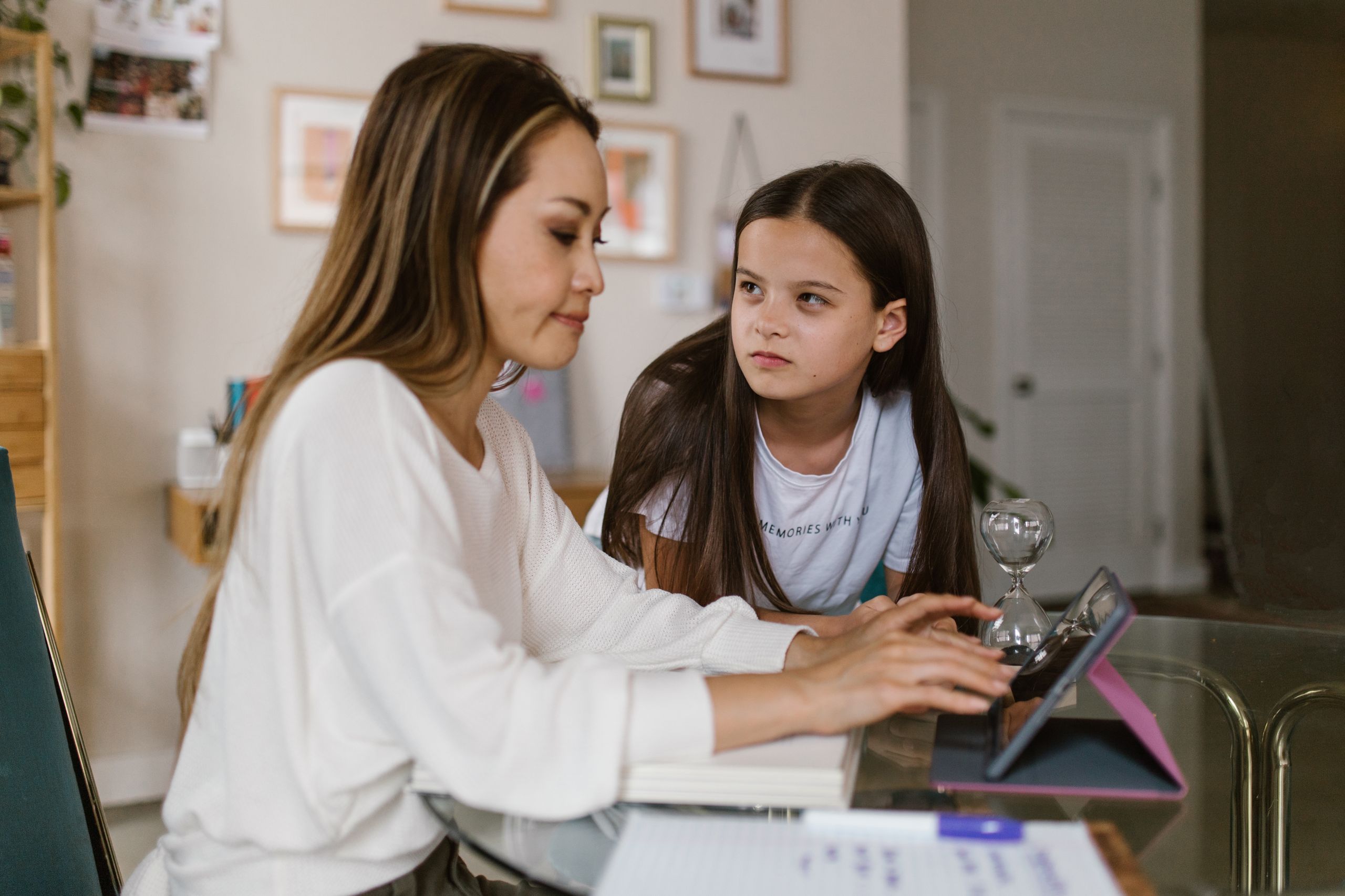 Mother and daughter engaged with a tablet at a home office setting.