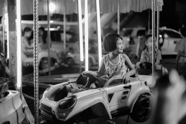 A young girl smiling on a carousel ride at night.