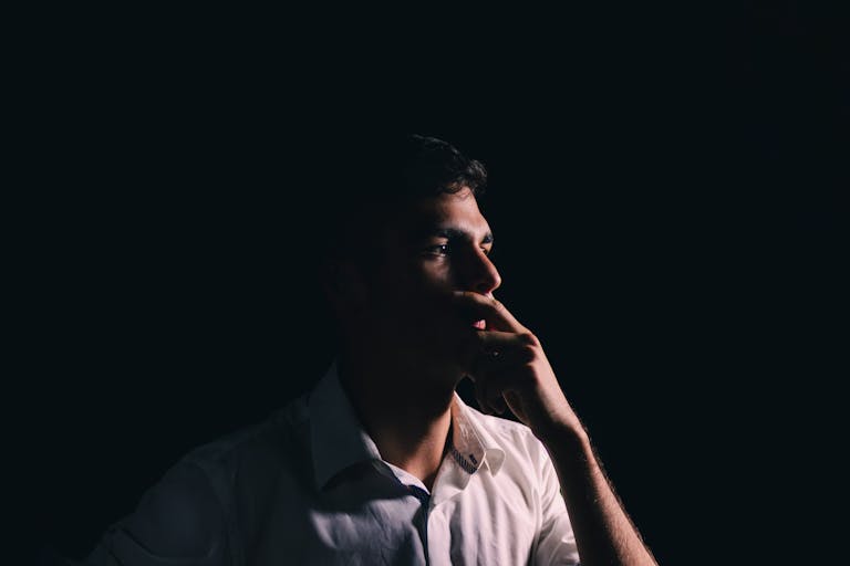 Portrait of a man thoughtfully posing against a dark background, highlighting introspection.