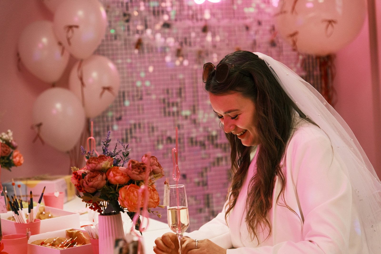 Smiling bride celebrating at a pink party with champagne.