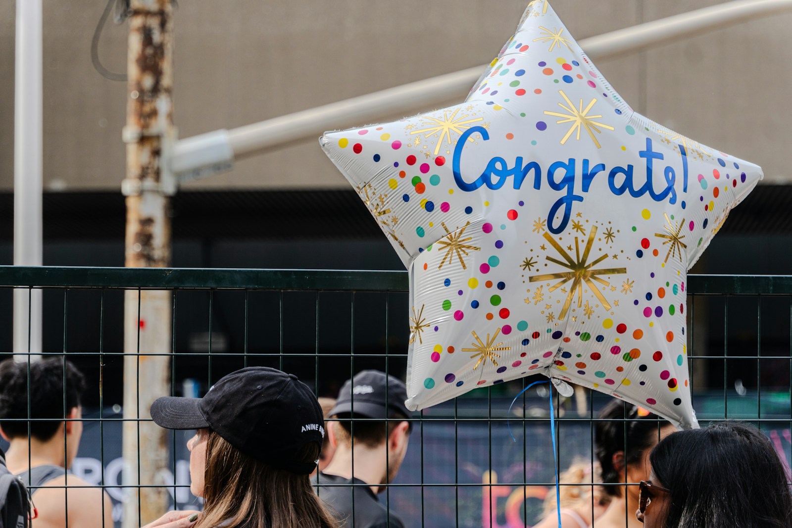 A star-shaped "congrats!" balloon floats above a crowd.