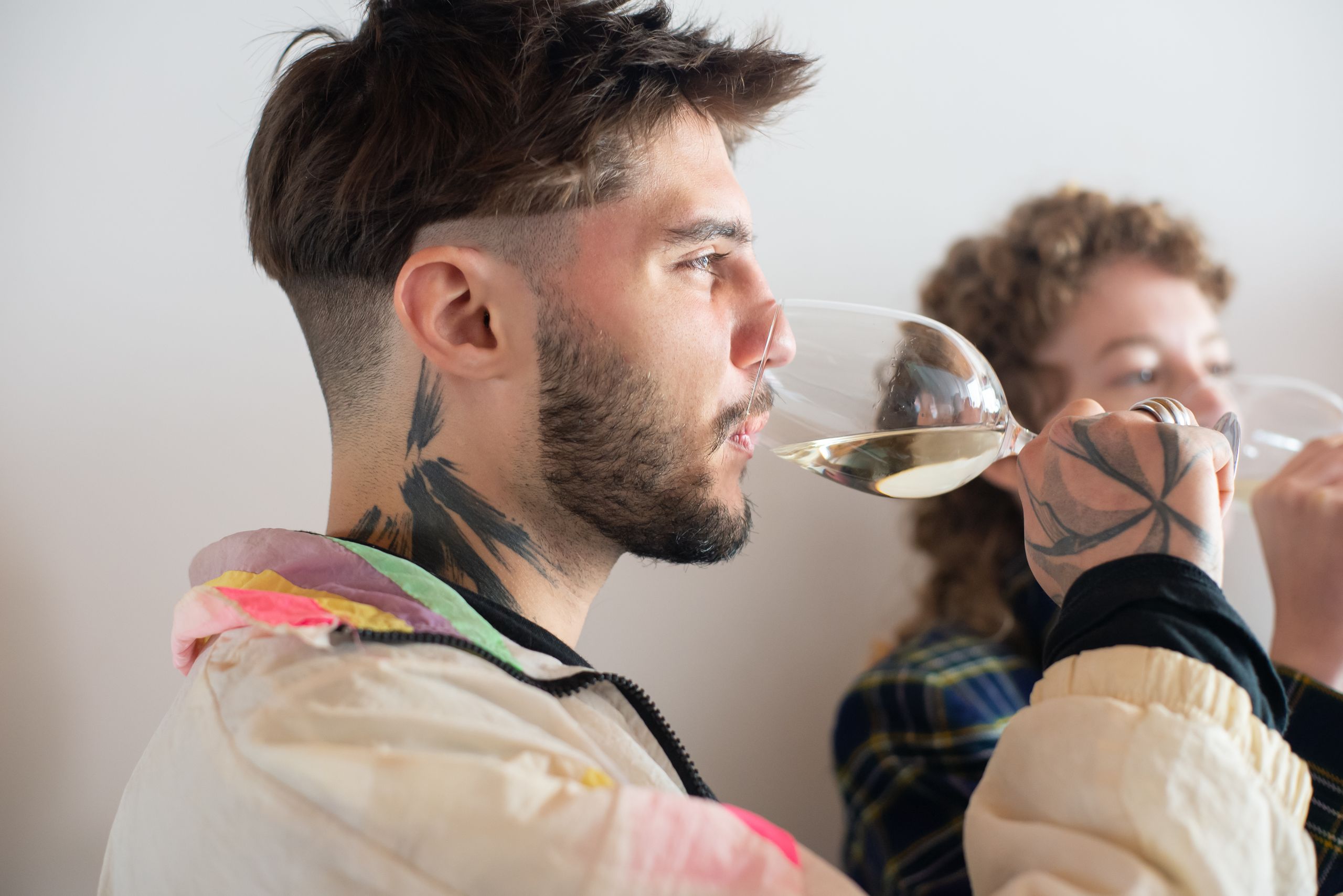 Side view of young adults enjoying a wine tasting experience indoors.