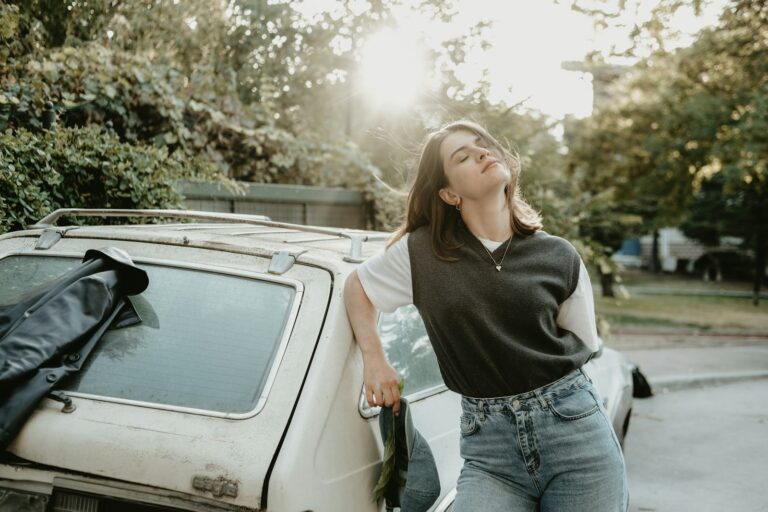 a woman leaning on the hood of a car