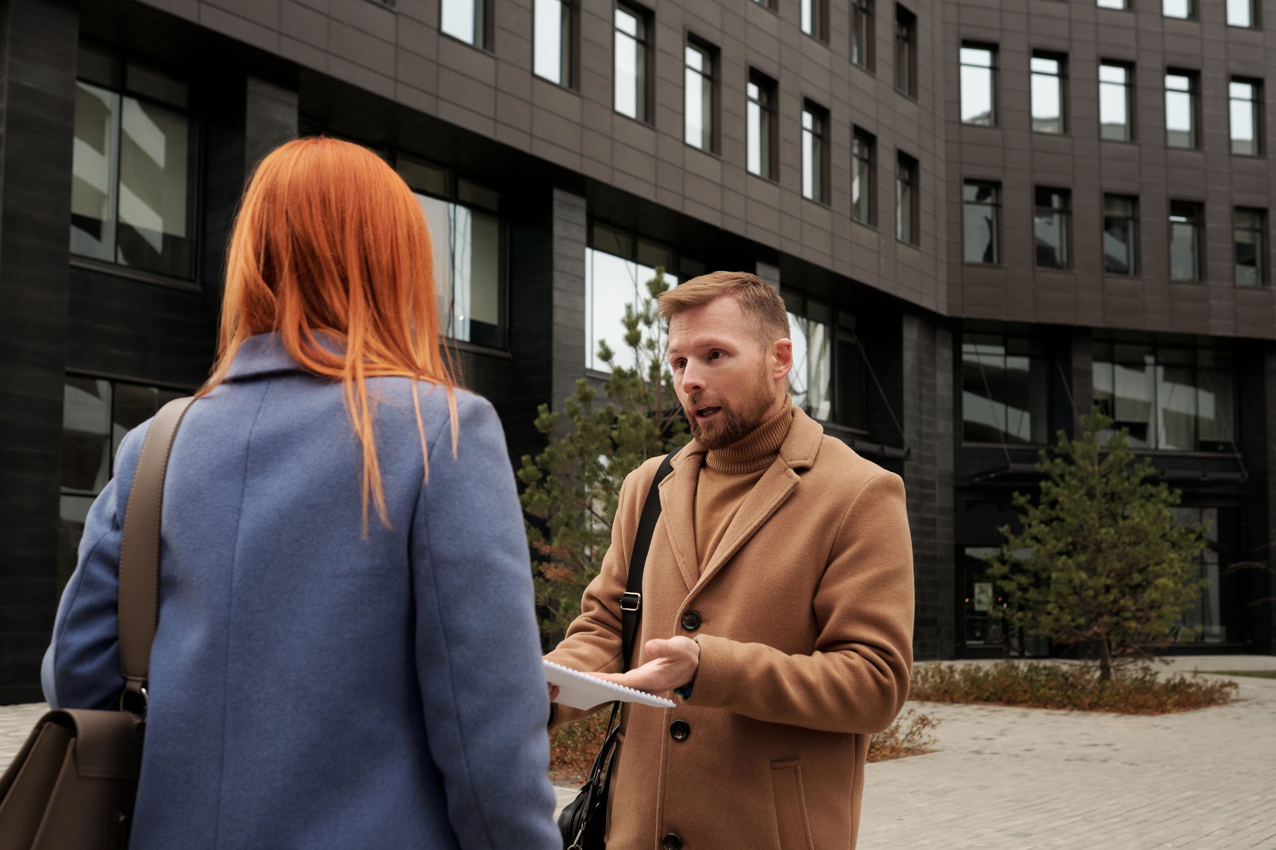 Two business professionals in conversation outside an urban office building.