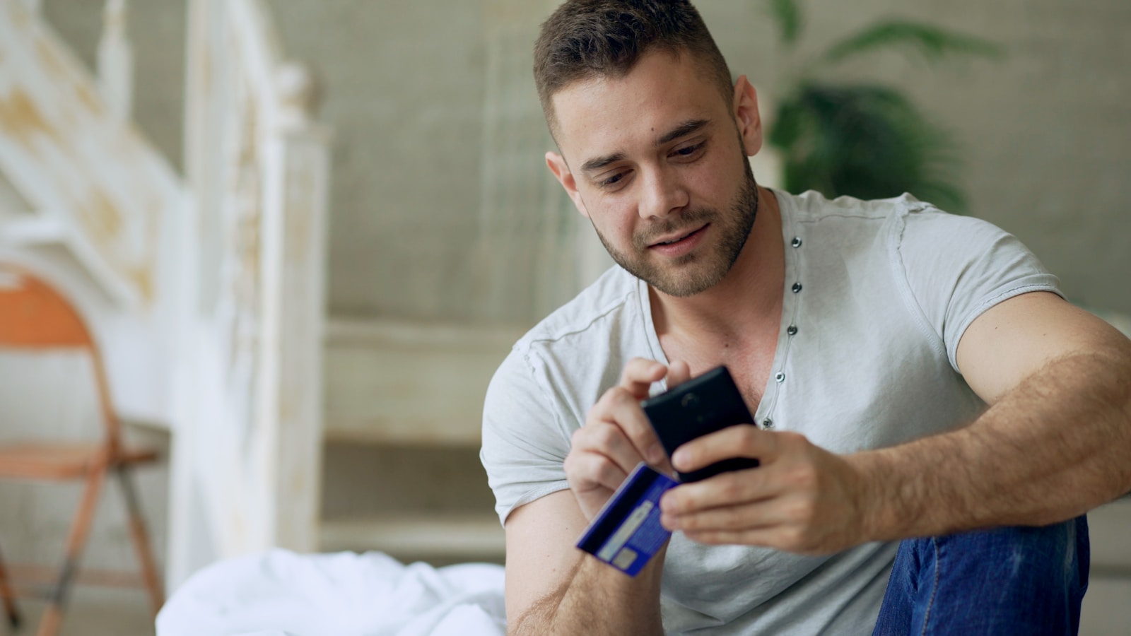 Man holding credit card and smartphone indoors