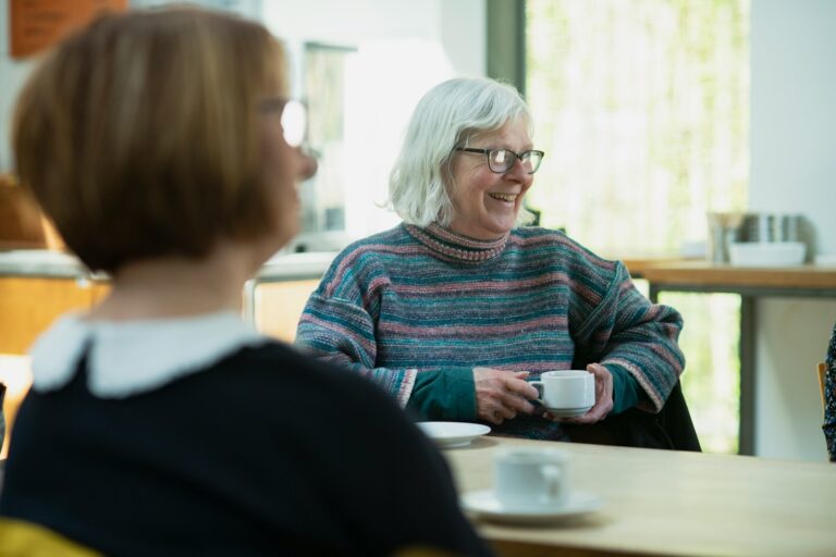 a woman sitting at a table with a cup of coffee
