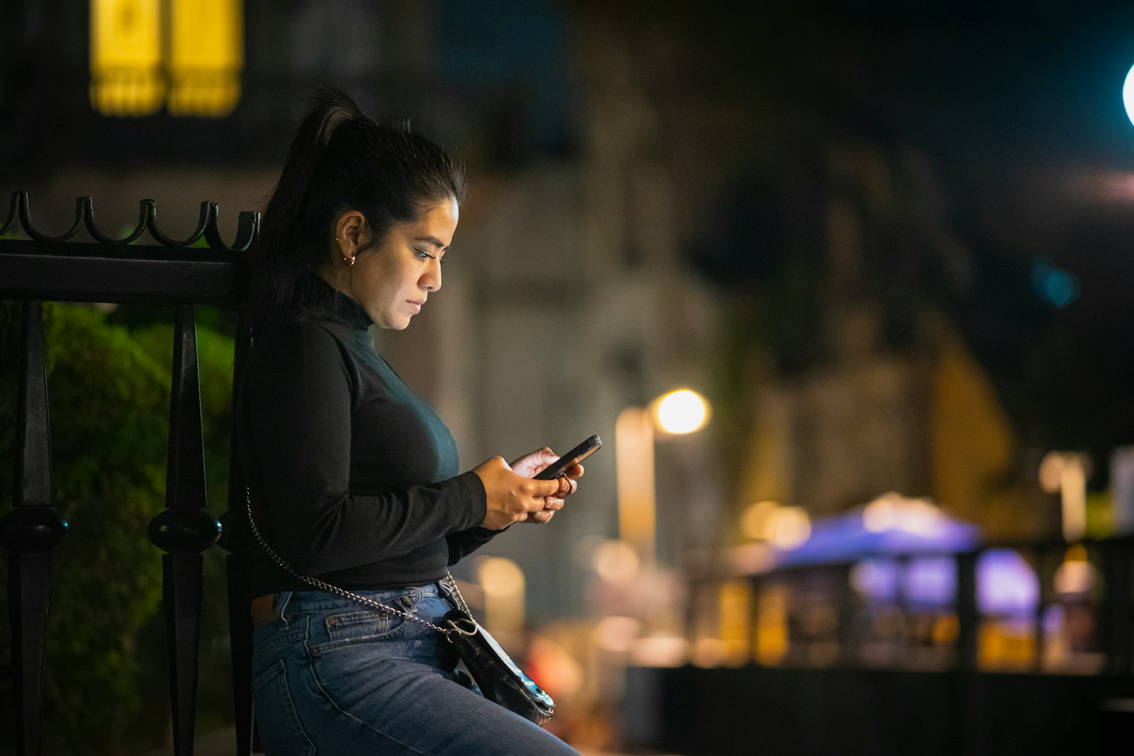 a woman sitting on a bench looking at her cell phone