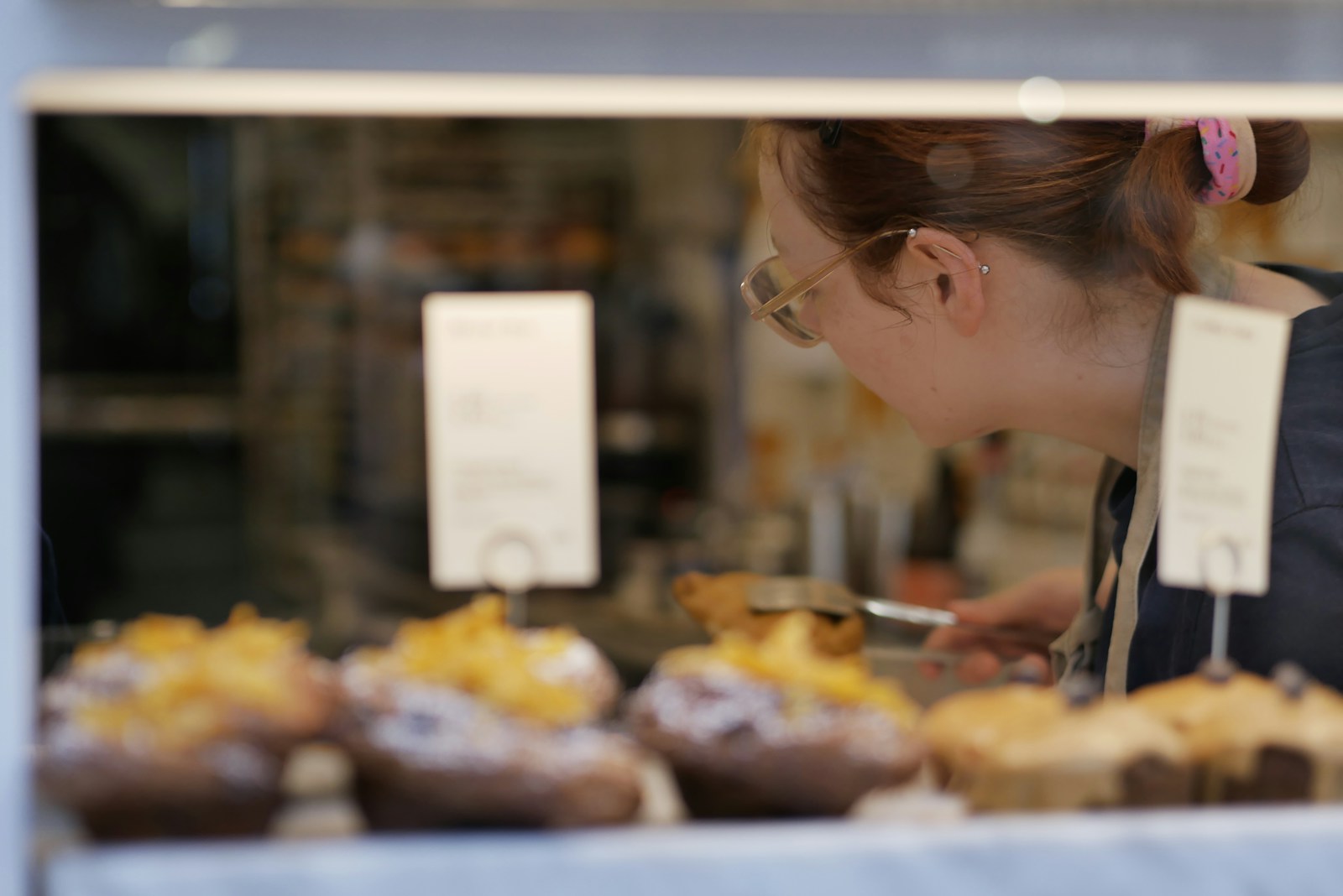 Baker arranging pastries in a display case.
