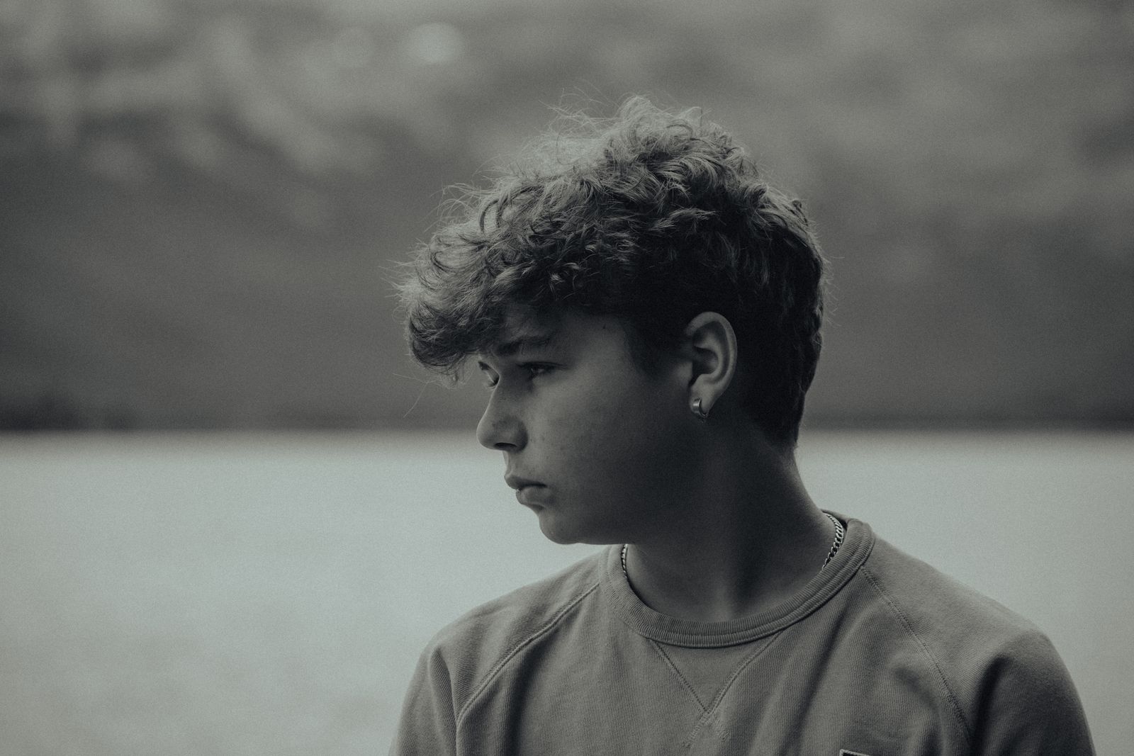 Side profile black and white portrait of a teenage boy outdoors, exuding a serene mood.