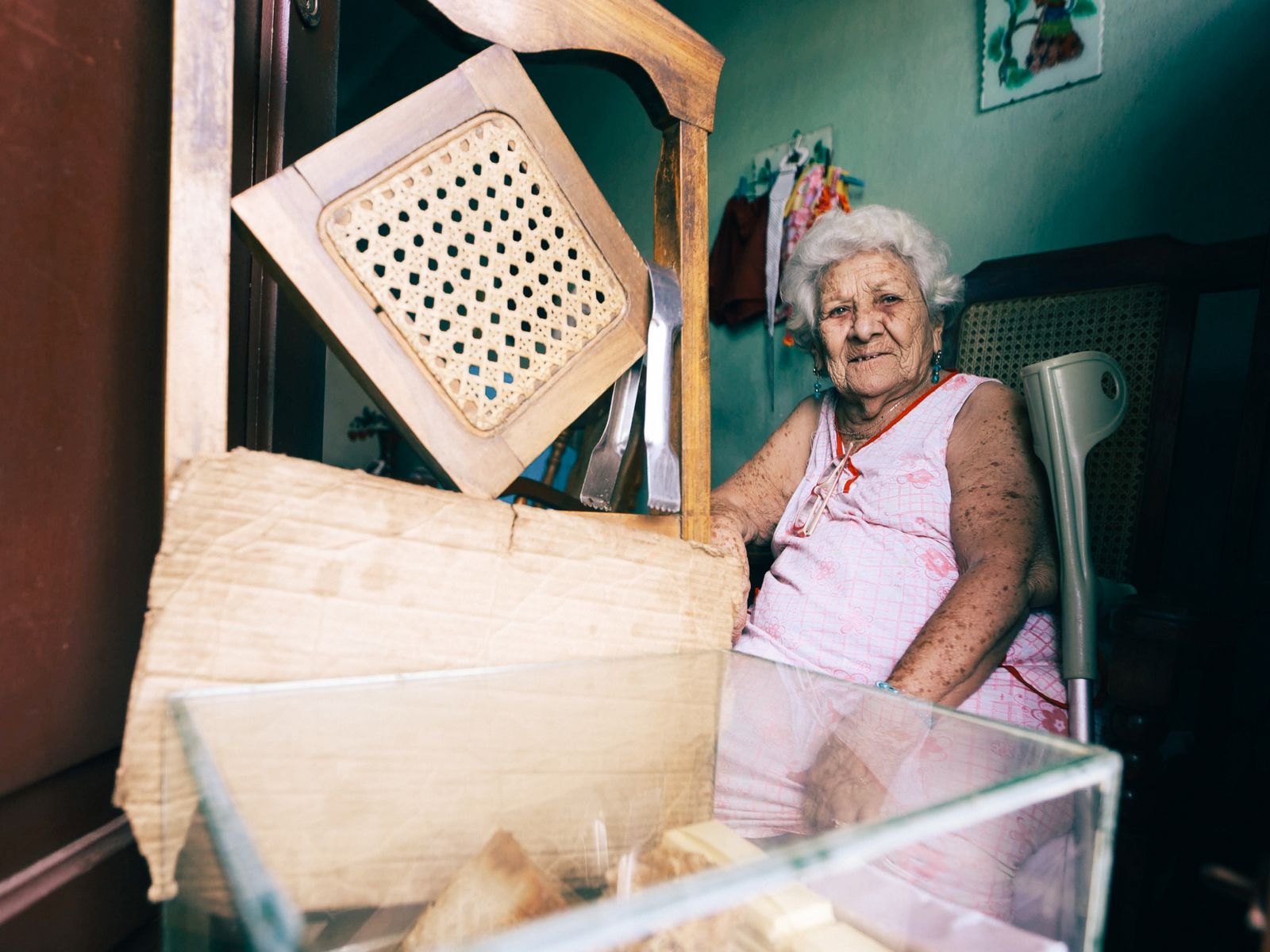 Senior woman sitting comfortably indoors surrounded by vintage furniture, exuding warmth and nostalgia.