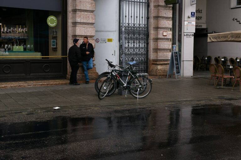 Two bicycles parked on a wet sidewalk.