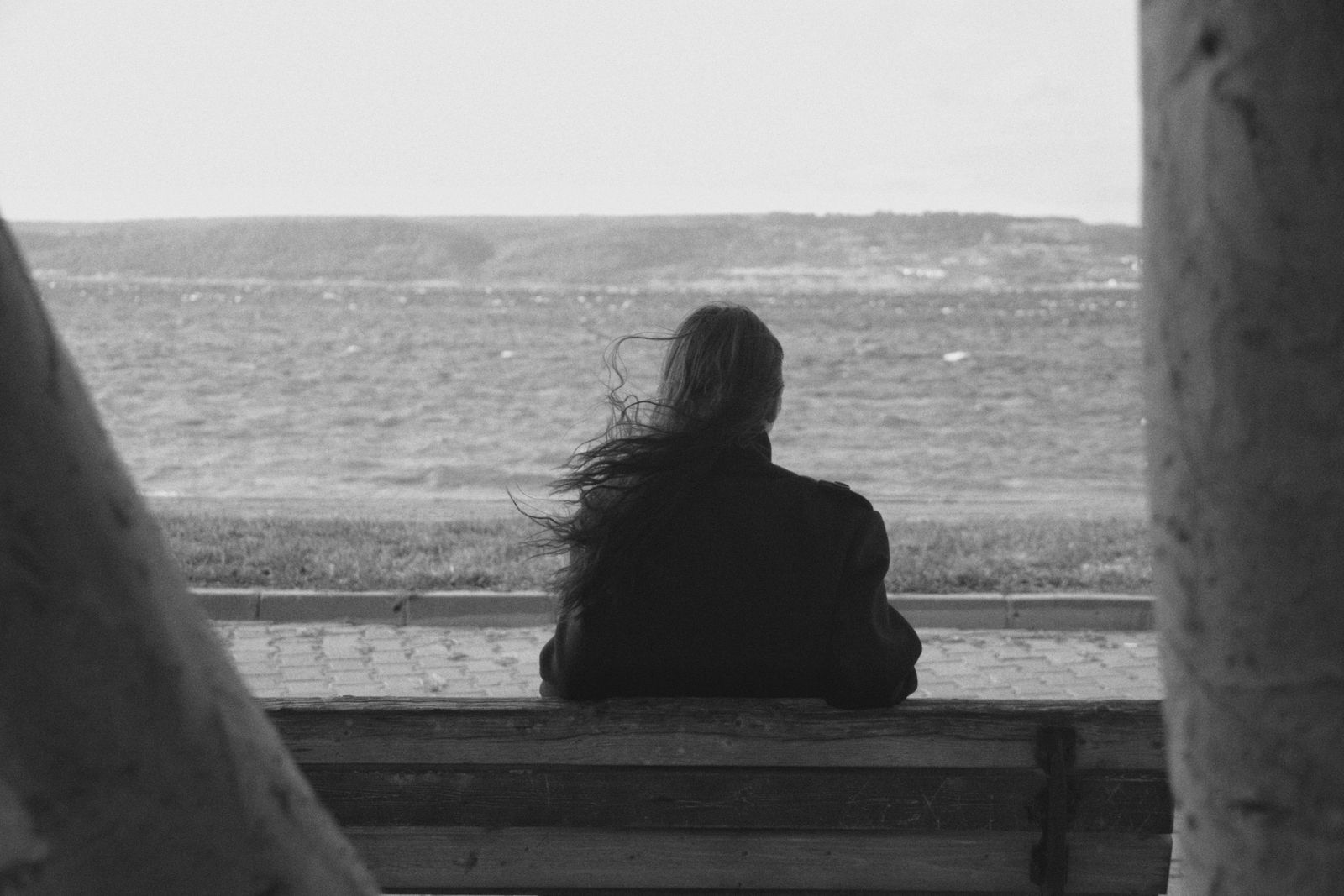 A solitary woman sits on a bench by the sea, embracing the serene landscape.