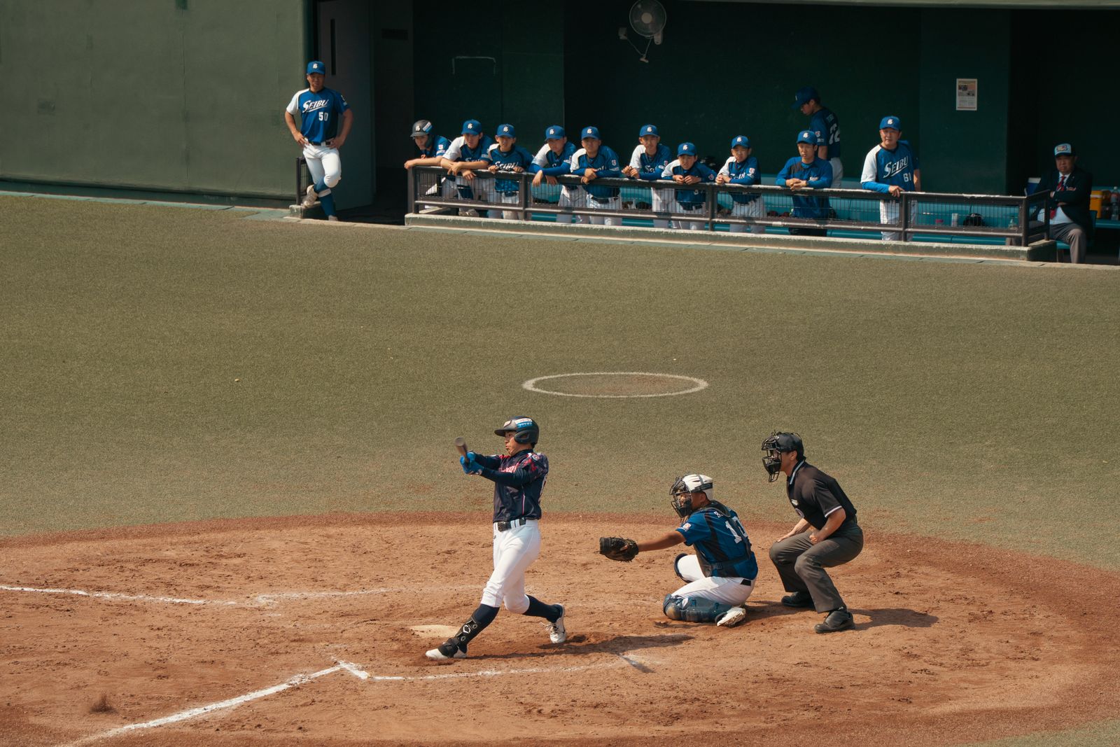 Baseball game action in Tokyo, capturing a batter, catcher, and umpire during a pitch.