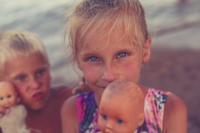 two little girls are playing with dolls on the beach