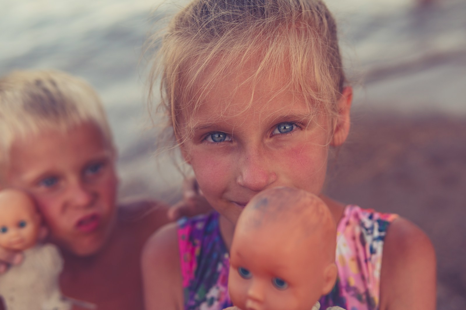 two little girls are playing with dolls on the beach