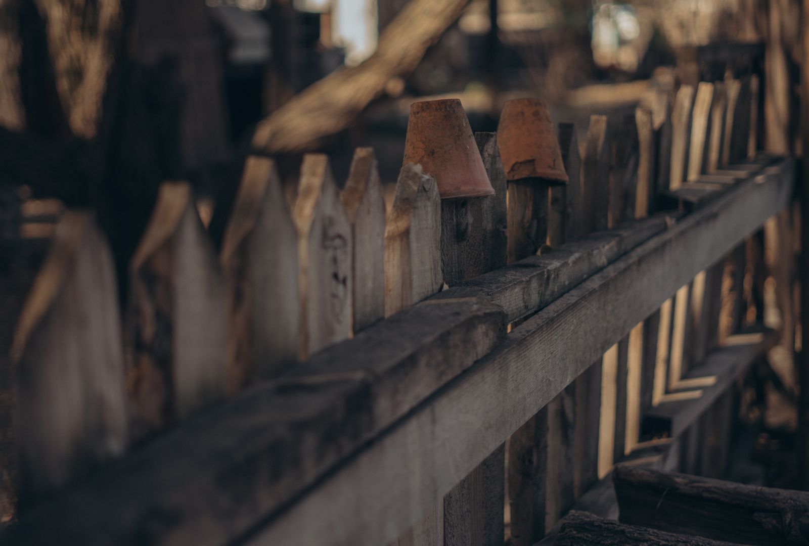 Shabby timber planks in old fence on blurred background of rural land in sunlight