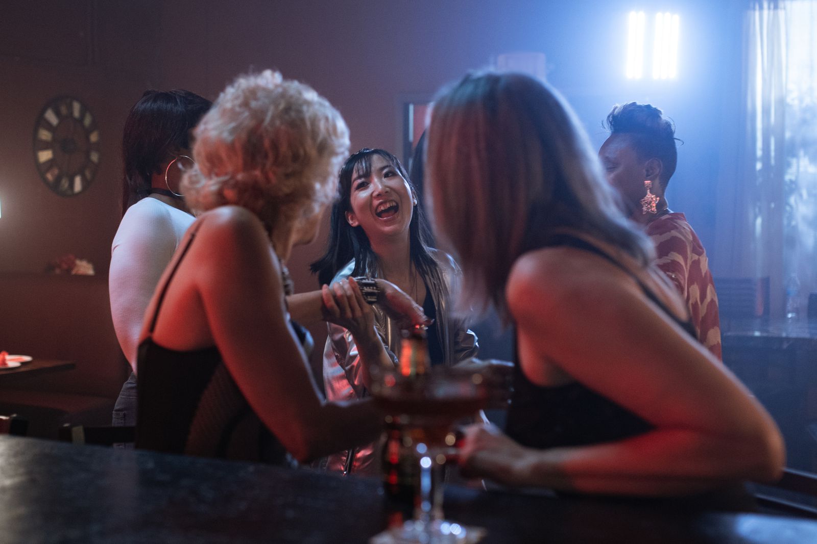A group of women enjoying a lively night out in a modern bar, filled with laughter and cocktails.