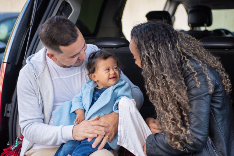 Joyful family bonding with baby sitting inside a car.