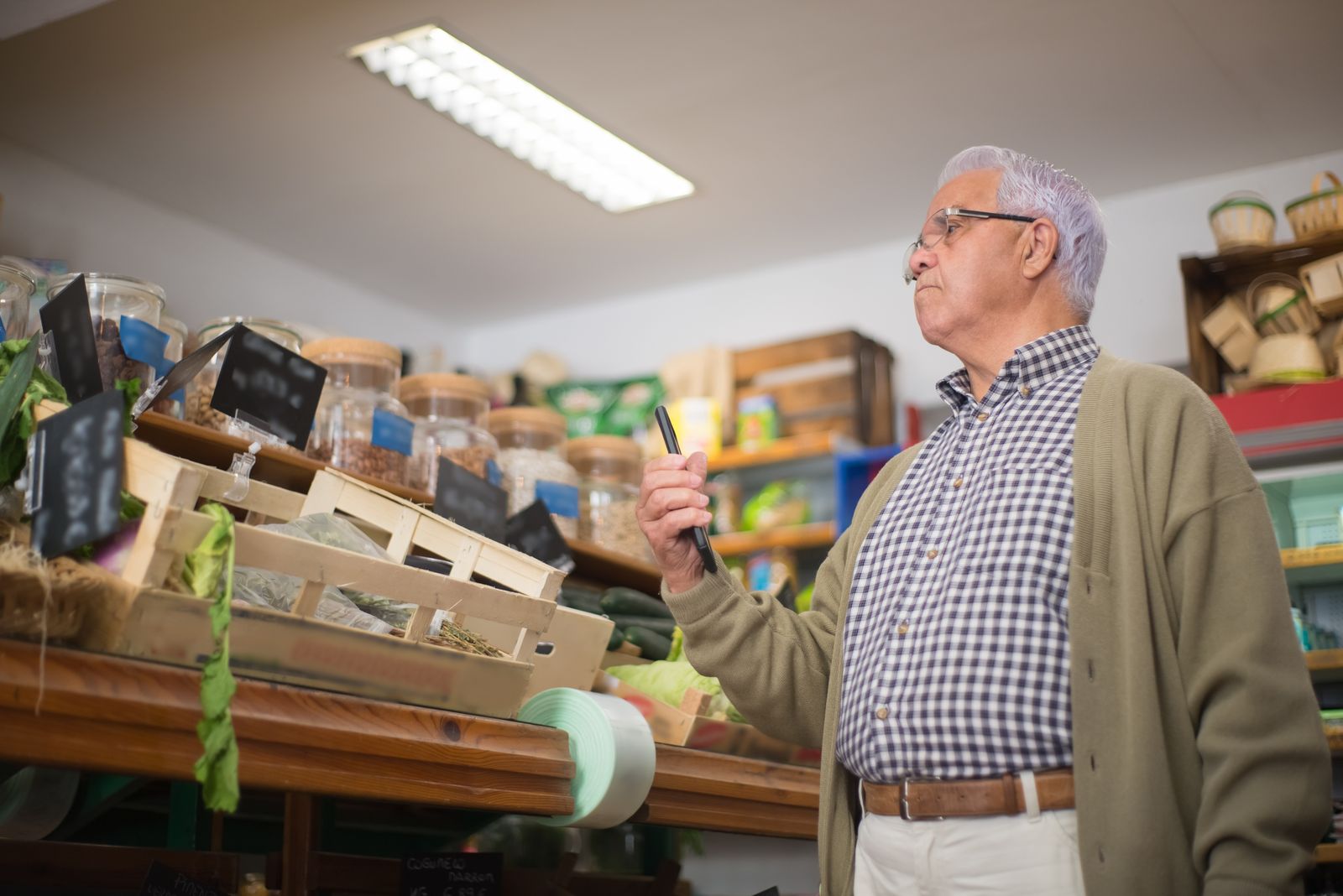 Senior man shopping in a Portuguese store, examining products with focus.