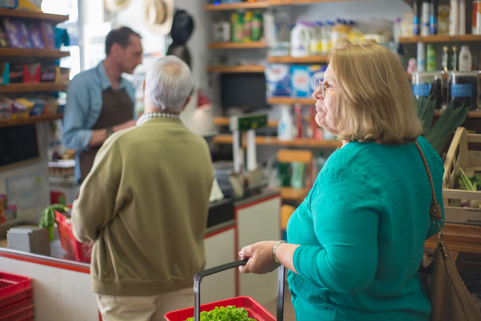 Senior woman with basket shopping in a cozy Portugal grocery store.
