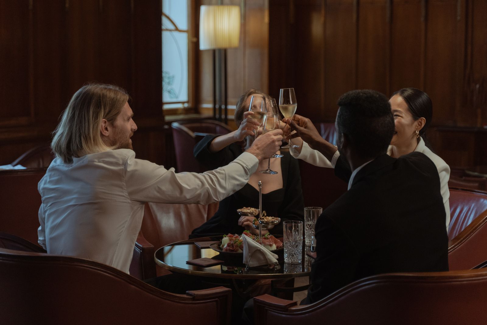A diverse group of friends celebrating and toasting with drinks indoors
