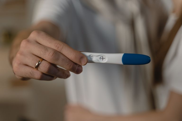 A close-up shot of a positive pregnancy test held by an expecting couple, symbolizing new life.