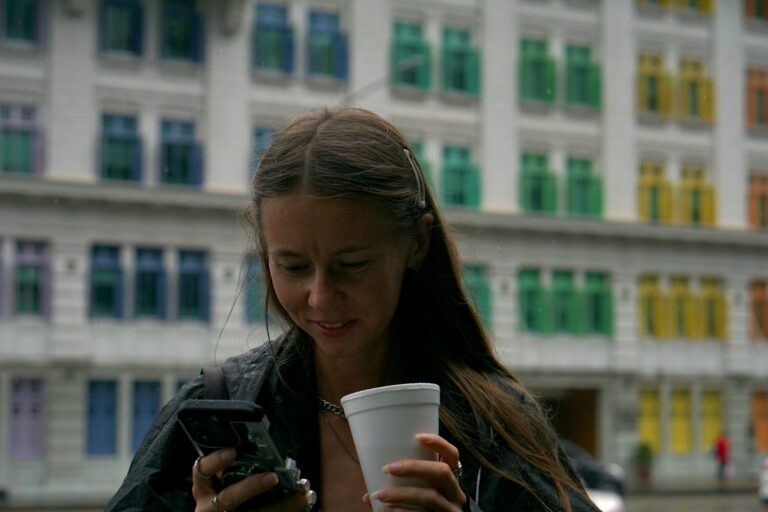 Woman holding drink and looking at phone