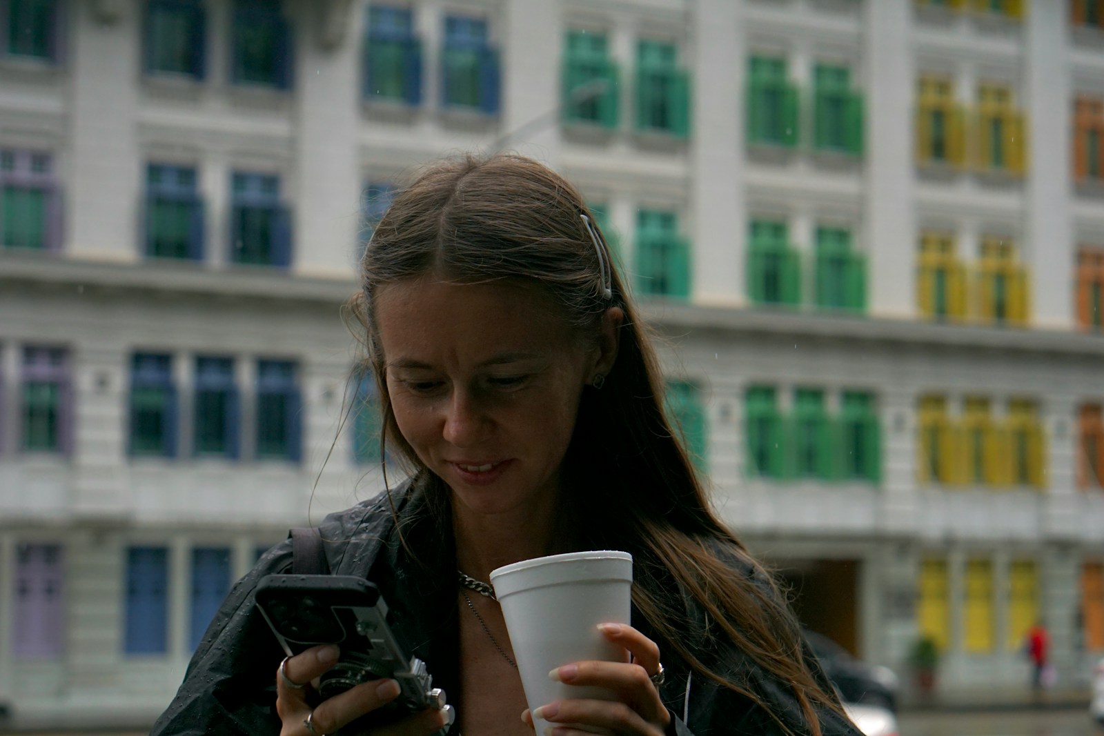 Woman holding drink and looking at phone