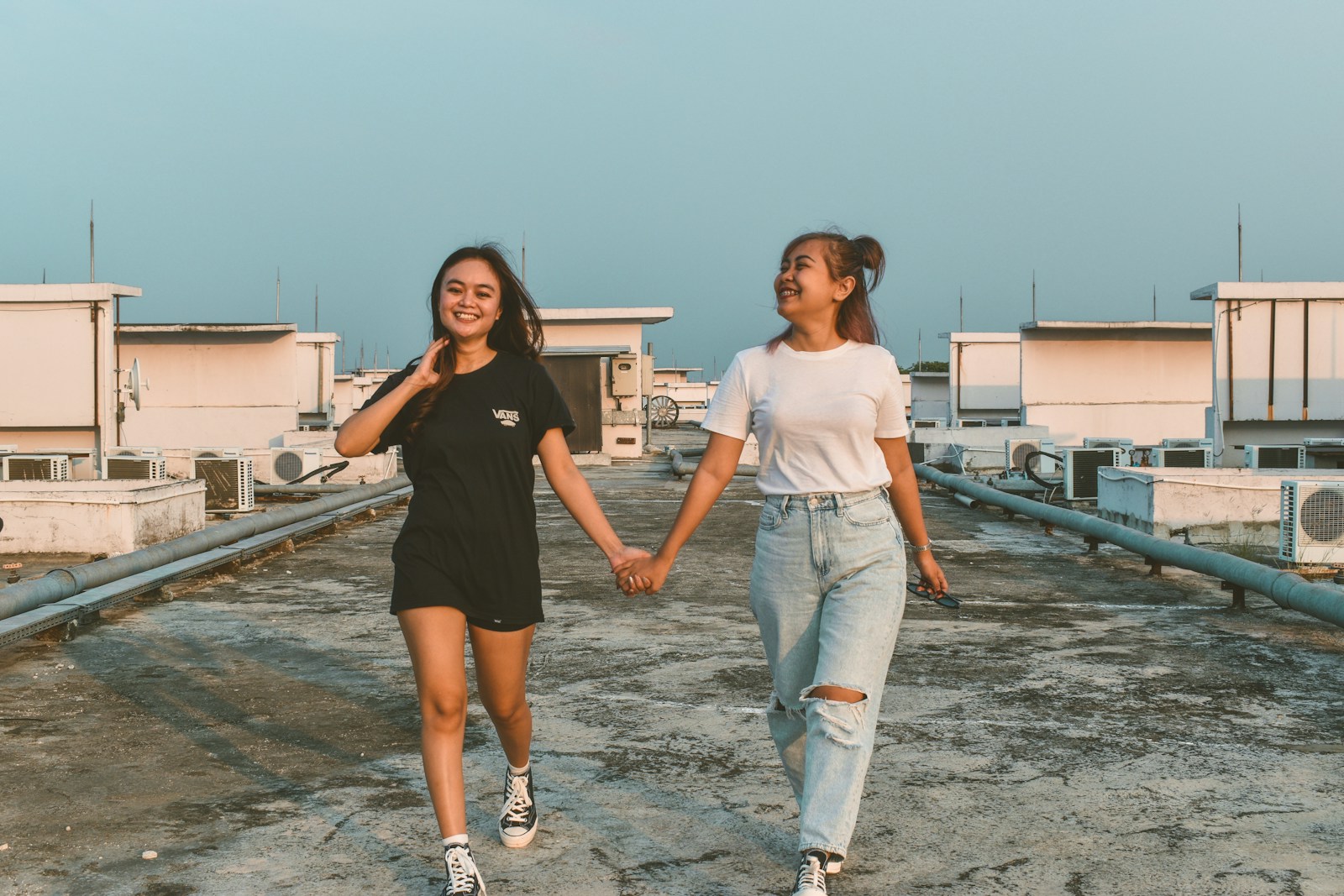 two young women holding hands while walking on a roof