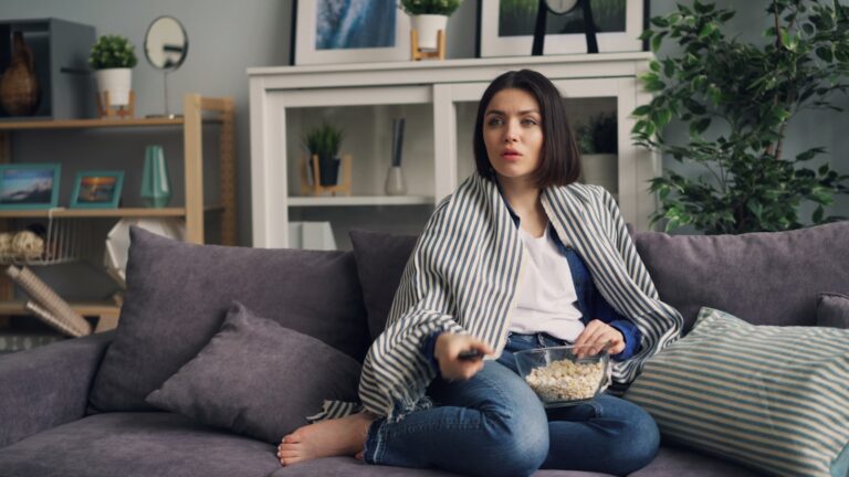 a woman sitting on a couch eating popcorn