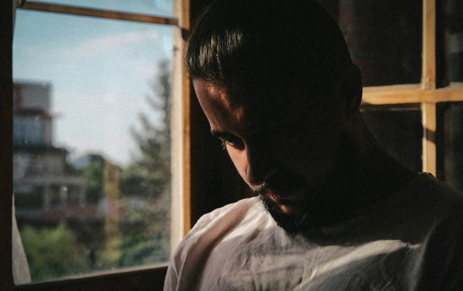 a man looking out of a window in a dark room