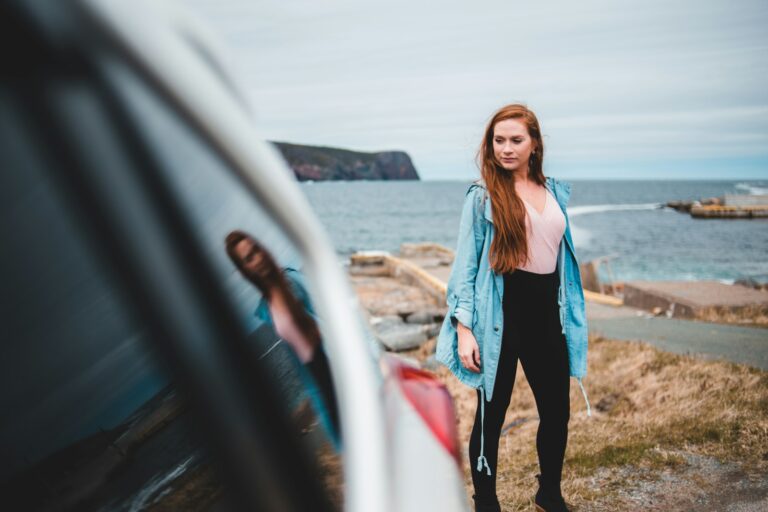 woman in blue jacket standing beside vehicle