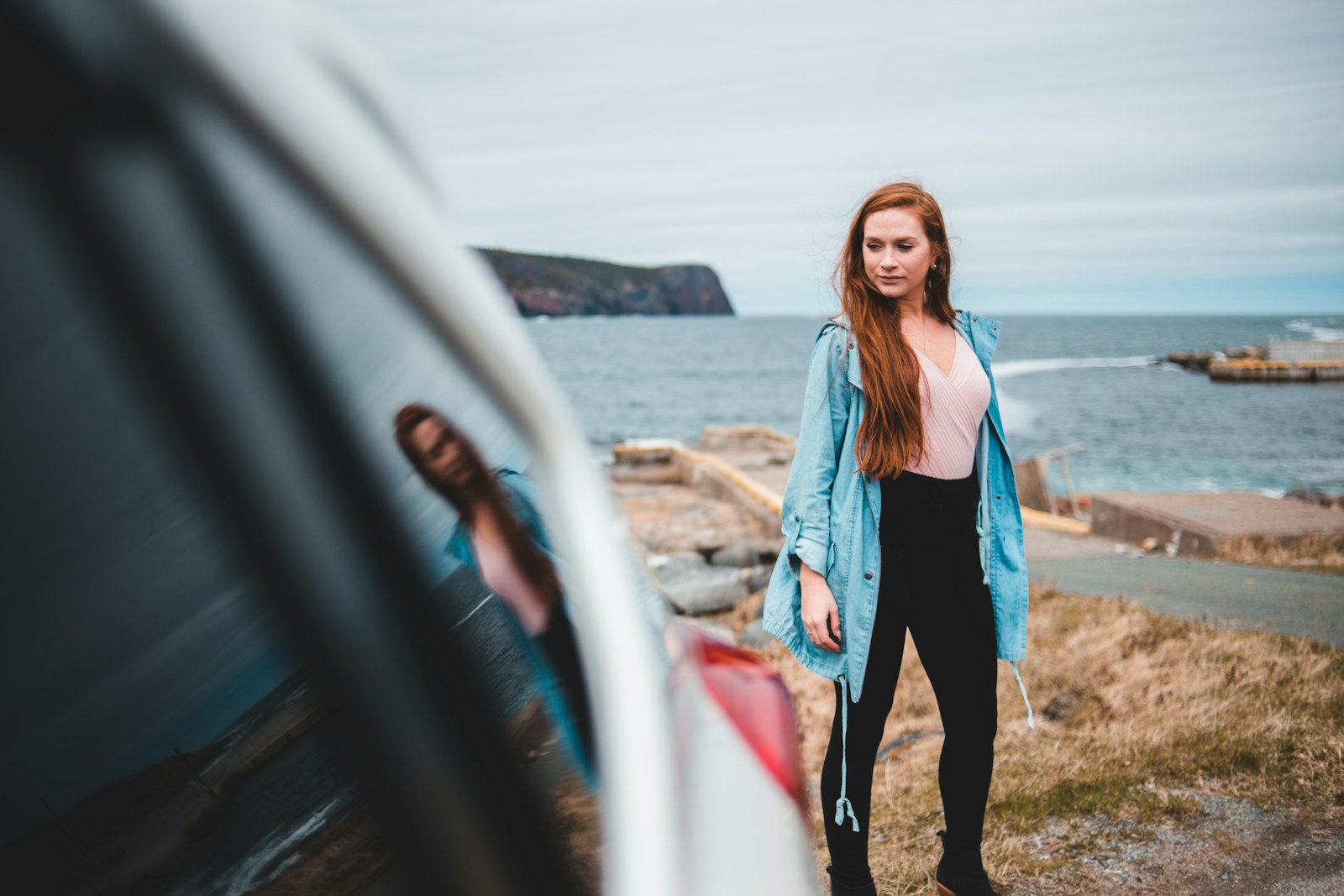 woman in blue jacket standing beside vehicle