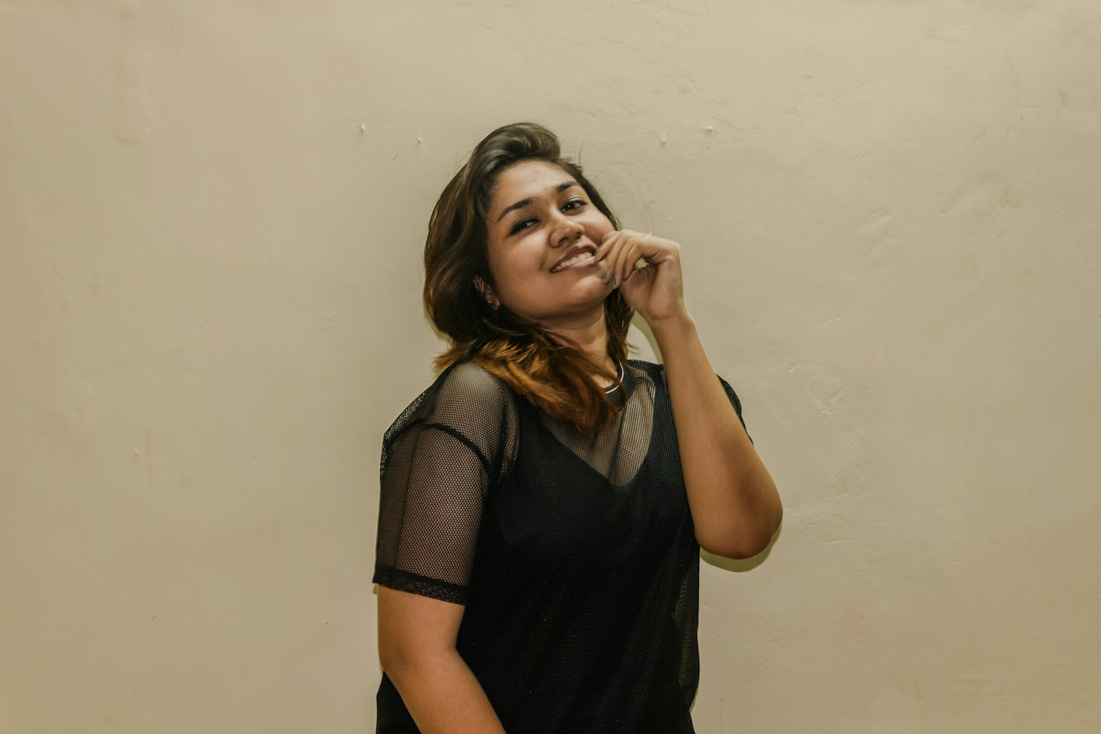 A woman standing in front of a wall talking on a cell phone