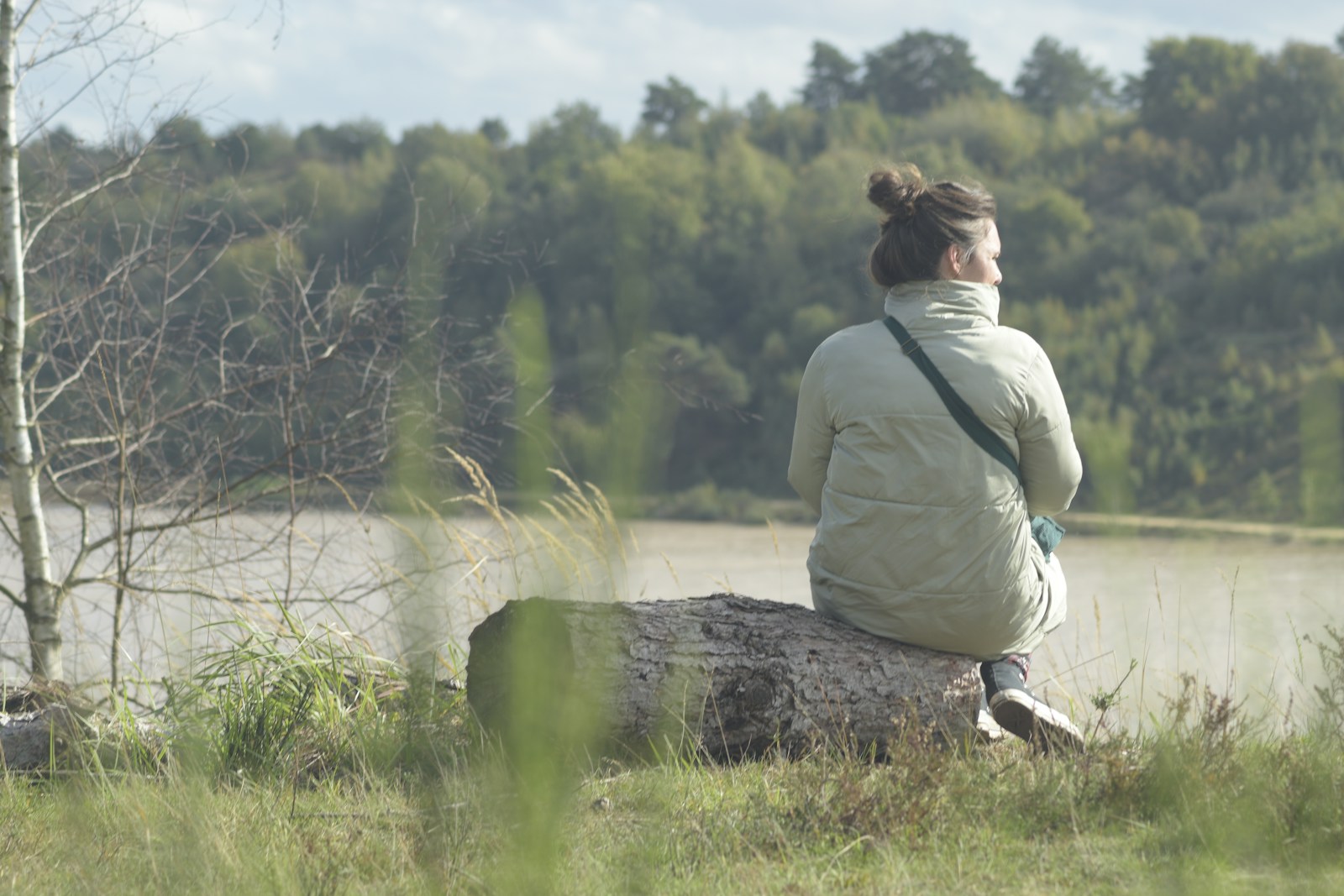 a woman sitting on a rock near a lake