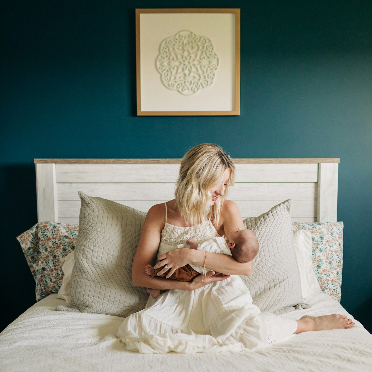 a woman sitting on a bed holding a baby