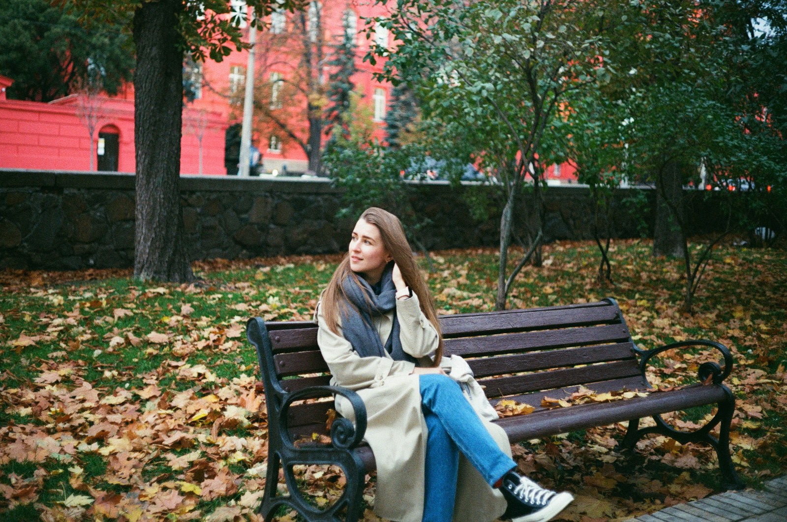 woman in brown coat sitting on brown wooden bench