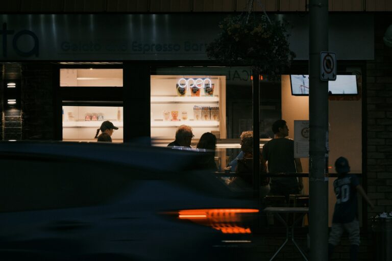 Evening cafe scene with people and passing car.