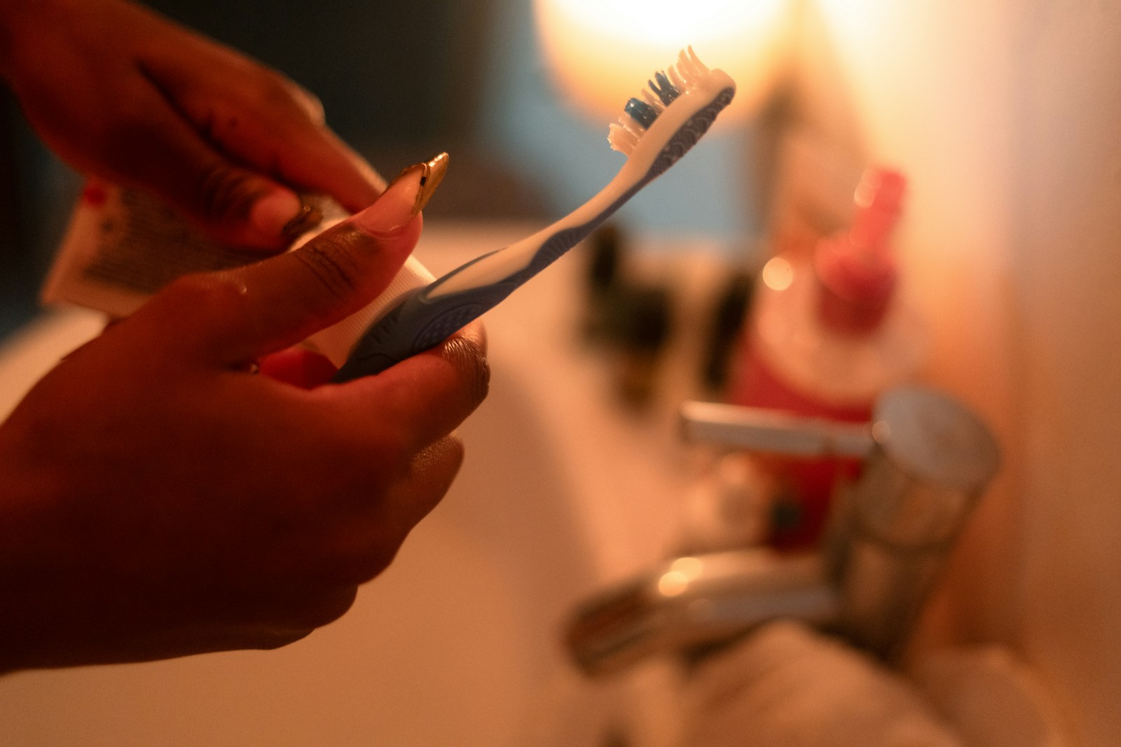 Hands squeezing toothpaste onto a toothbrush