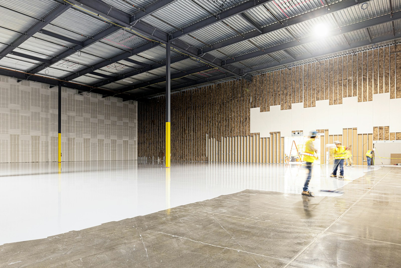 Two construction workers in a large empty warehouse