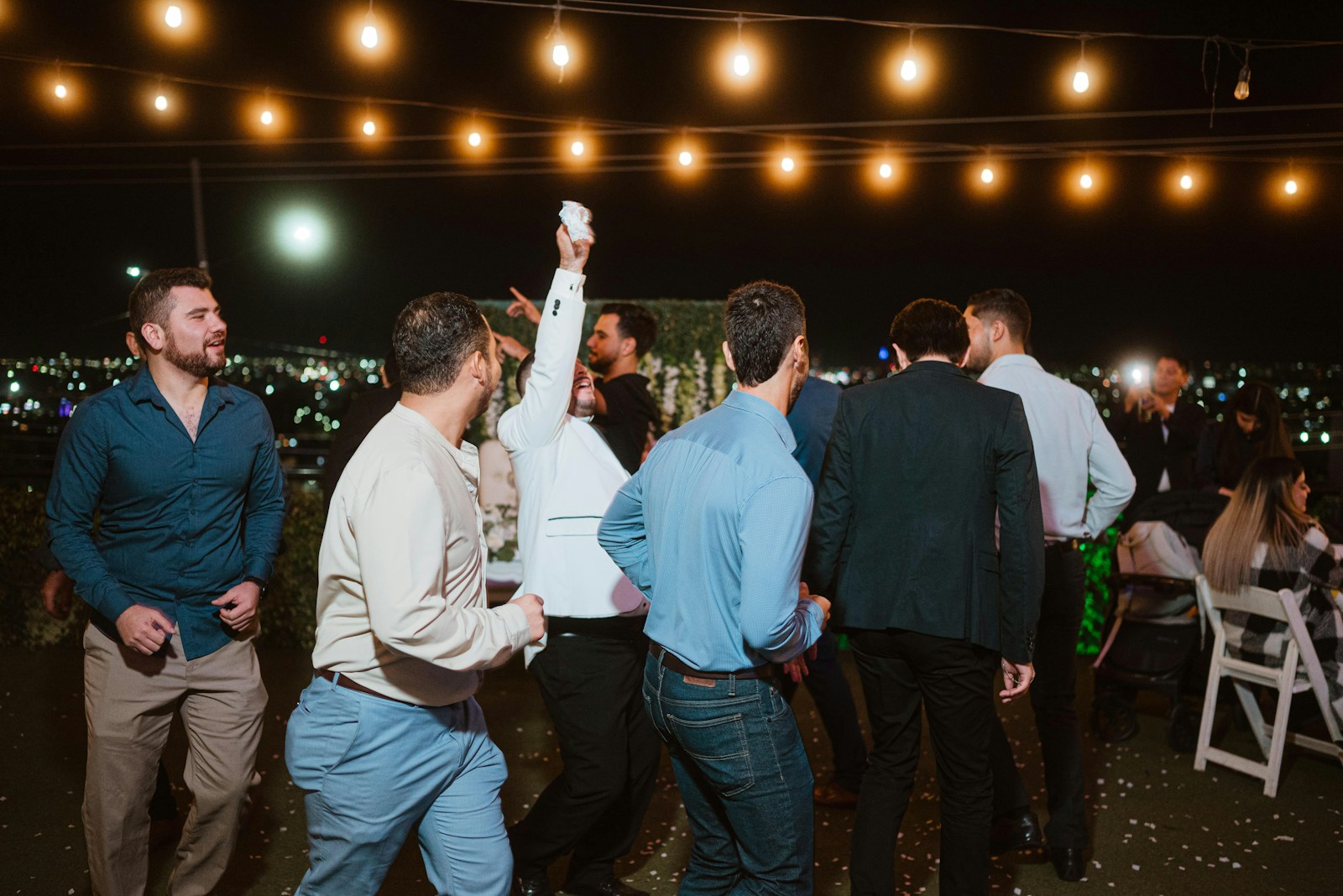 Men dancing under string lights at night
