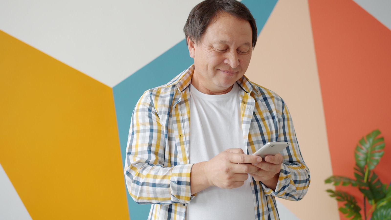 Man in checkered shirt using smartphone indoors