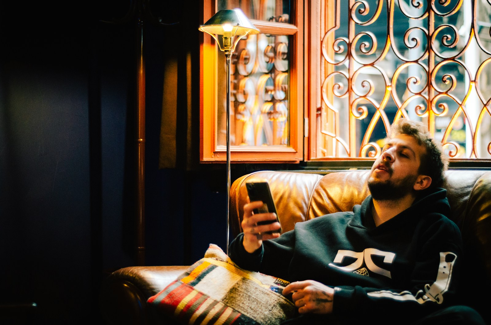 a man sitting on a couch looking at a cell phone