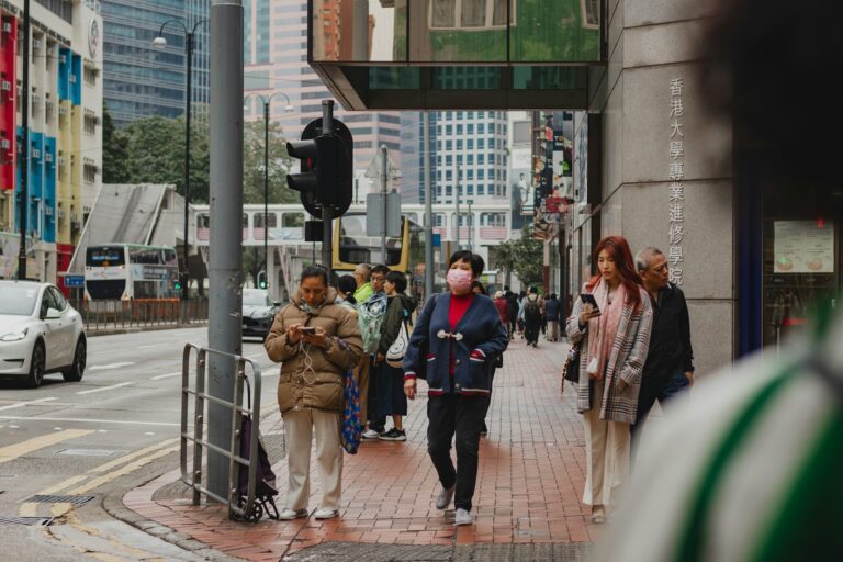 A group of people walking down a street next to a traffic light