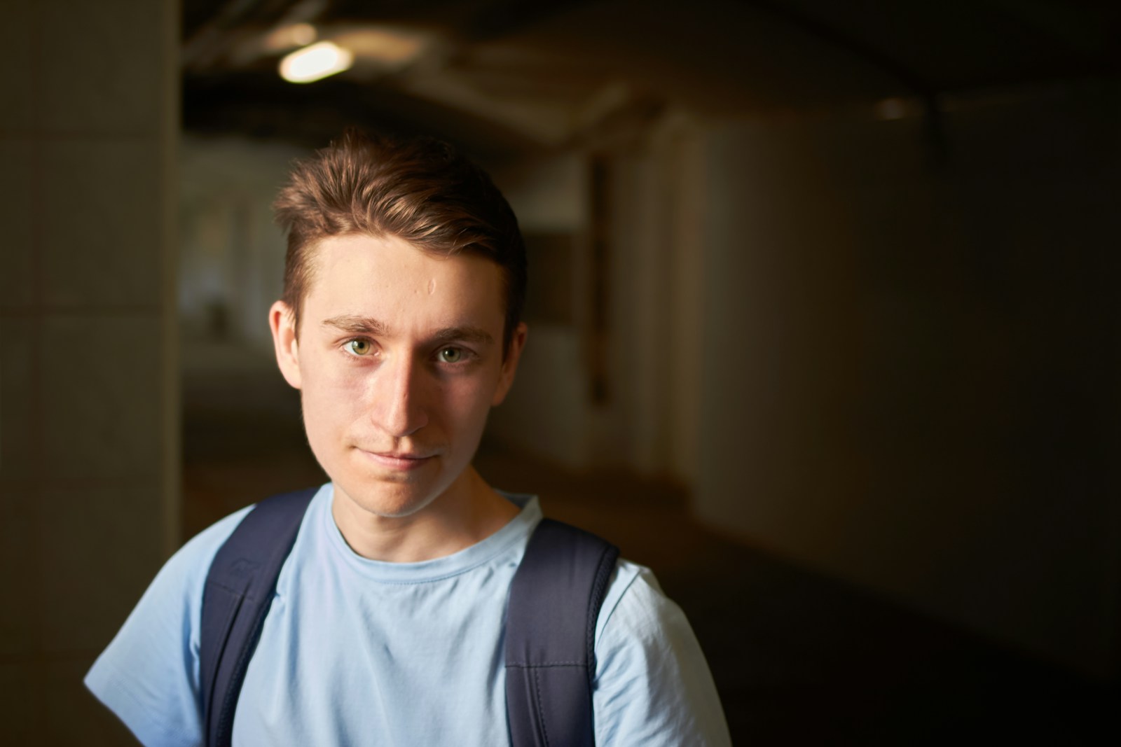 Young man stands in a dark corridor.