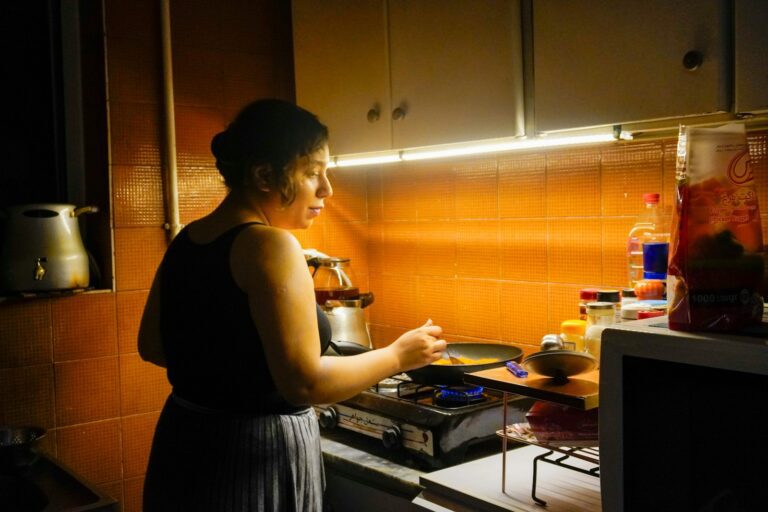 A woman cooks food in a small kitchen.