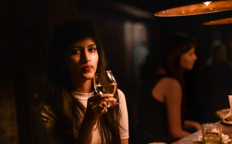 a woman sitting at a table holding a glass of wine