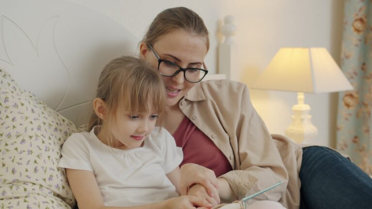 Mother and daughter reading a book in bed.