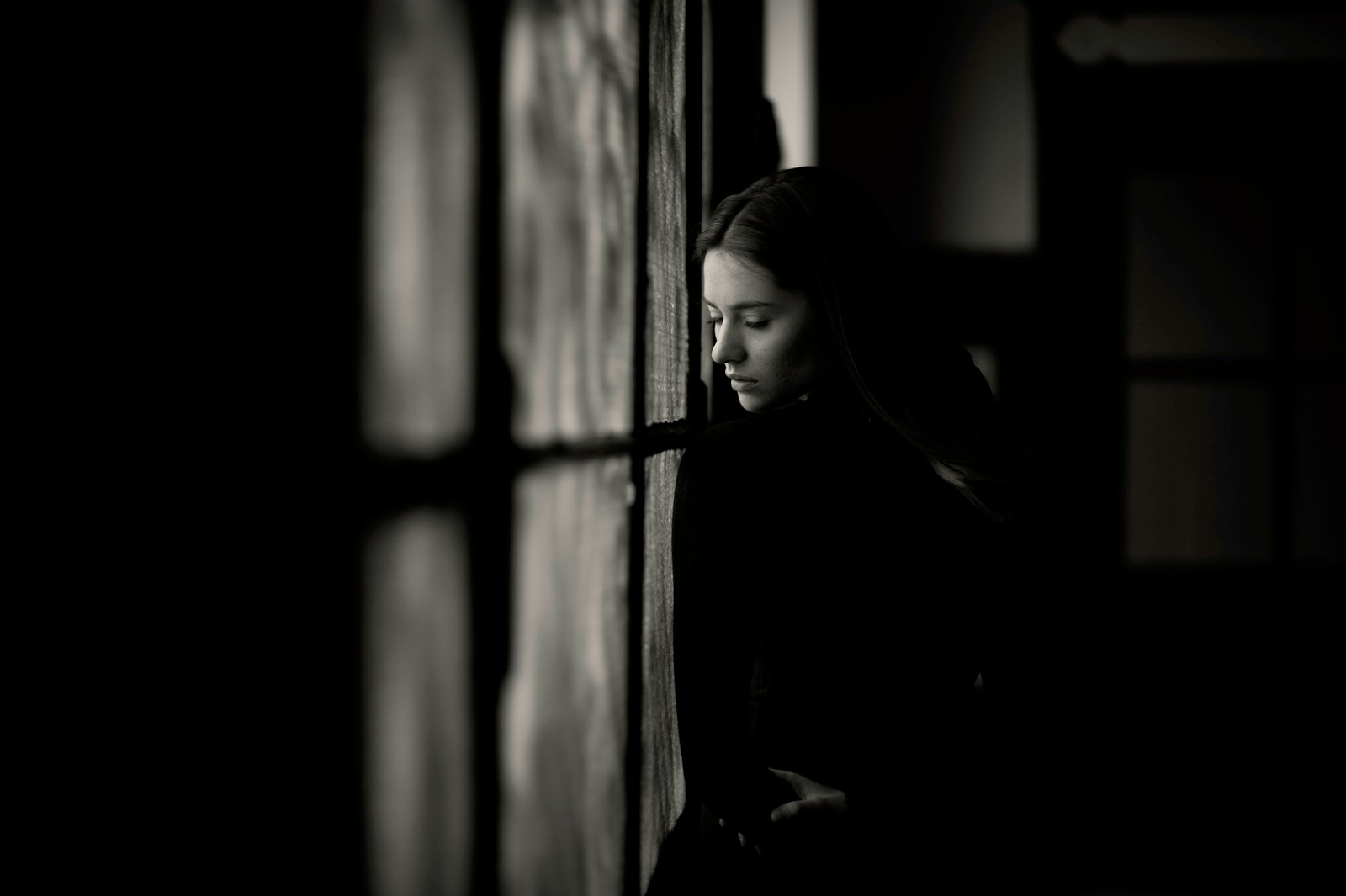 a woman leaning against a wall in a dark room