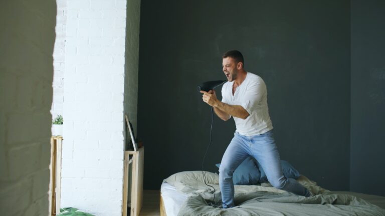 Man playing video game on bed with controller on bed